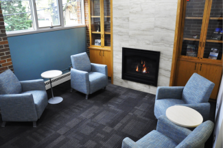 A reading room with comfortable lounge chairs, cabinets, and a fireplace.